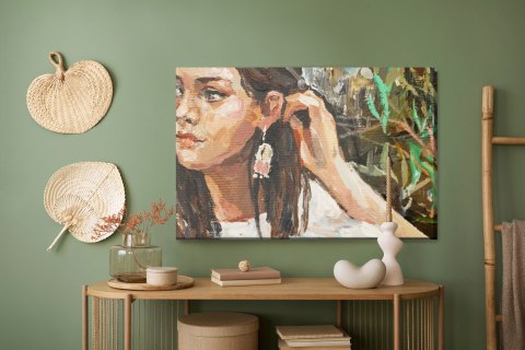 Obraz Na Płótnie A Young Girl Is Sitting In An Ethnic White Dress. The Background Depicts An Autumn Field With Flowers And Herbs Obraz Na Płótnie A Young Girl Is Sitting In An Ethnic White Dress. The Background Depicts An Autumn Field With Flowers And Herbs
